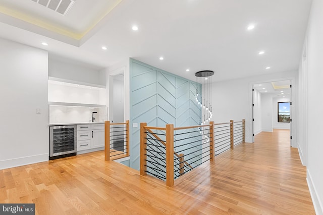 hall with sink, beverage cooler, and light wood-type flooring