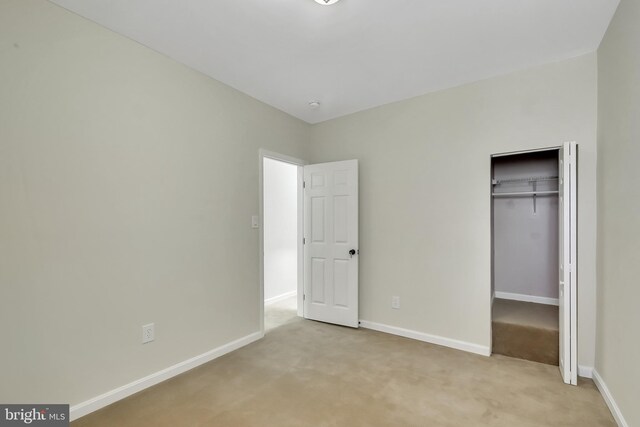 unfurnished bedroom featuring light colored carpet and a closet