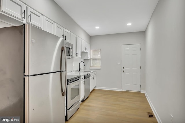 kitchen with white cabinetry, appliances with stainless steel finishes, sink, and light hardwood / wood-style floors