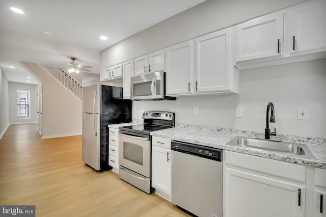 kitchen featuring appliances with stainless steel finishes, sink, white cabinets, and light hardwood / wood-style floors