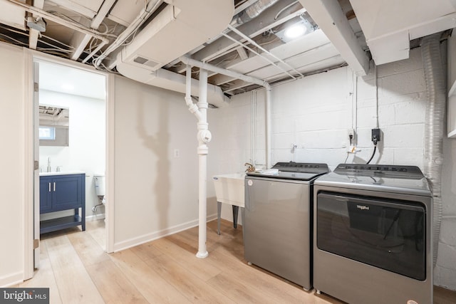 laundry area featuring separate washer and dryer, sink, and light wood-type flooring