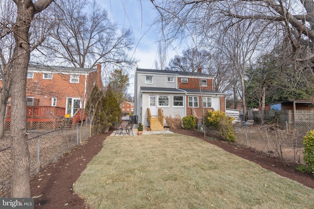 rear view of house featuring a wooden deck and a lawn