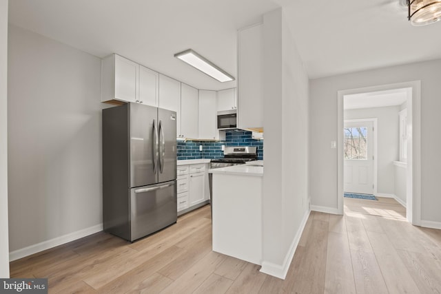 kitchen with white cabinetry, decorative backsplash, light hardwood / wood-style floors, and appliances with stainless steel finishes