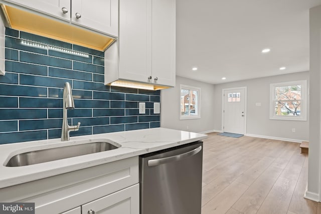 kitchen featuring tasteful backsplash, dishwasher, sink, white cabinets, and light stone counters