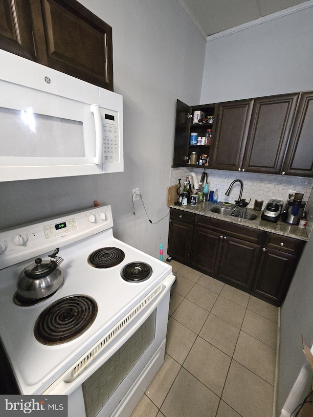 kitchen featuring light tile patterned flooring, tasteful backsplash, sink, dark brown cabinetry, and white appliances