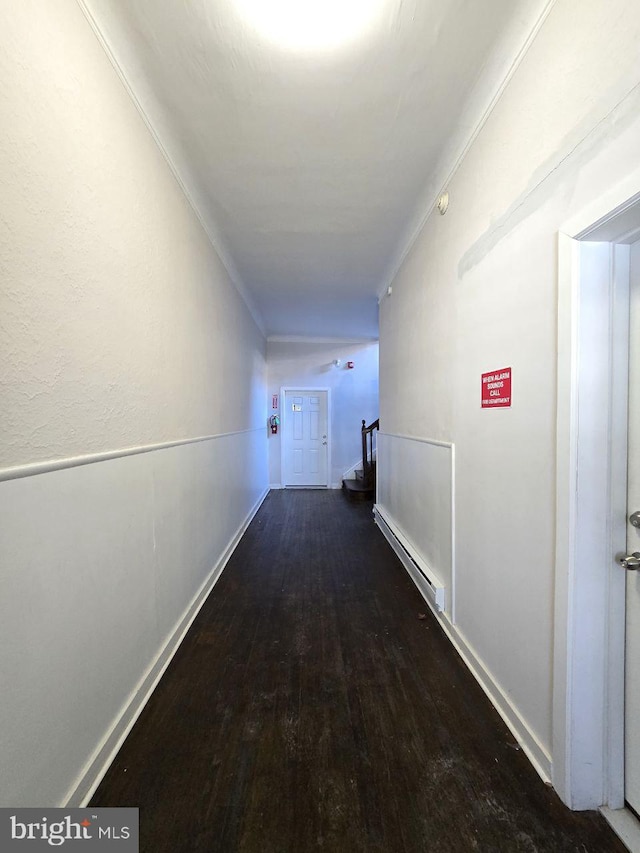 corridor featuring ornamental molding, dark hardwood / wood-style flooring, and a baseboard heating unit