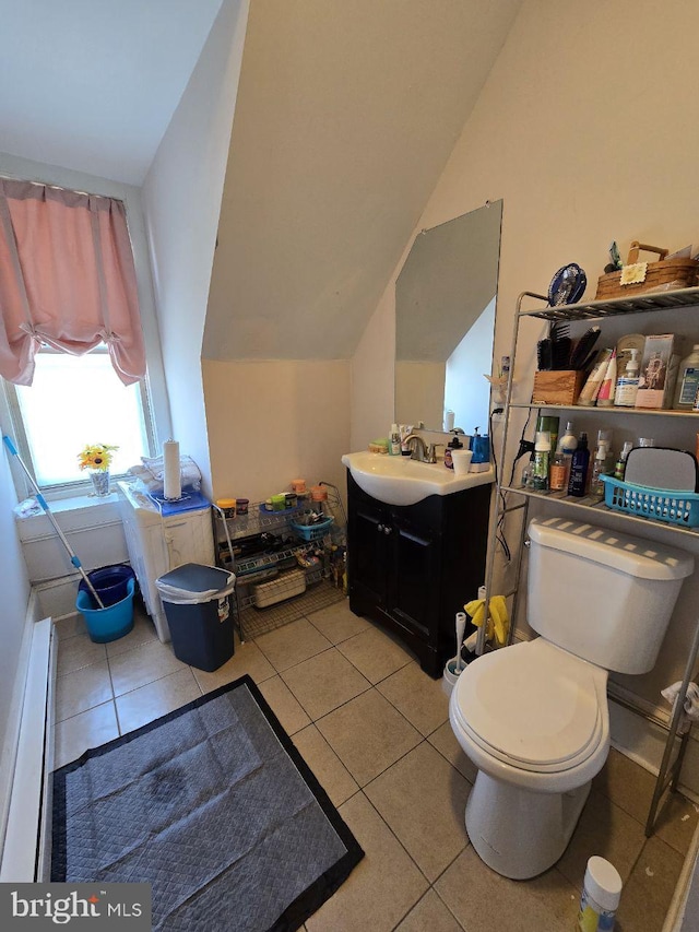 bathroom with tile patterned flooring, vanity, lofted ceiling, and toilet