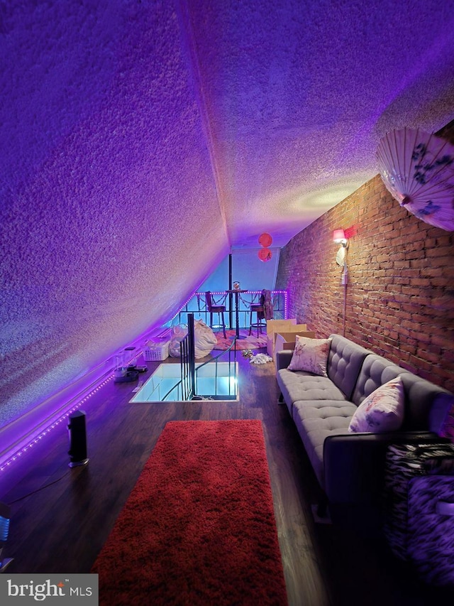 cinema room with lofted ceiling, hardwood / wood-style flooring, and a textured ceiling