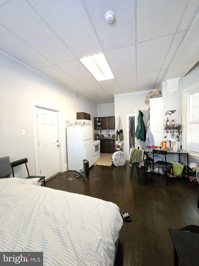 bedroom featuring hardwood / wood-style floors, a paneled ceiling, and white fridge