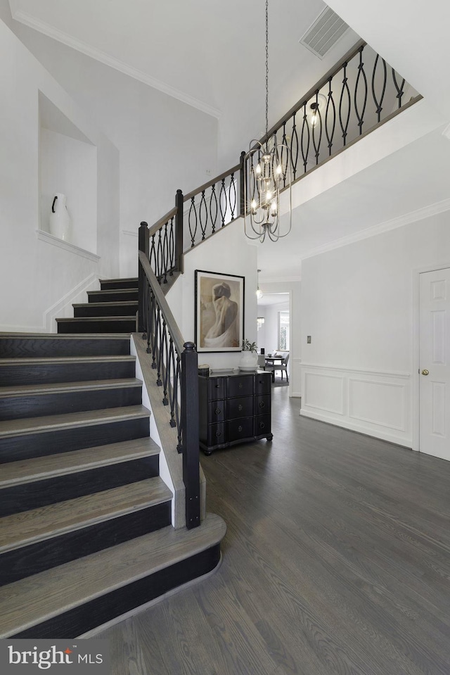 stairs with hardwood / wood-style flooring, ornamental molding, and a chandelier