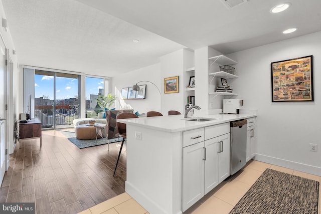 kitchen featuring open shelves, light countertops, white cabinetry, a sink, and dishwasher