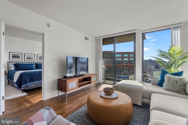 living room with baseboards, visible vents, floor to ceiling windows, and hardwood / wood-style floors