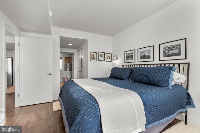 bedroom featuring hardwood / wood-style floors, ensuite bath, and baseboards