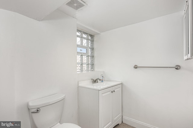 half bath featuring toilet, baseboards, visible vents, and vanity