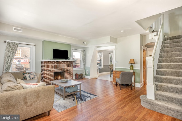 living room with a wealth of natural light, stairway, light wood-type flooring, and visible vents