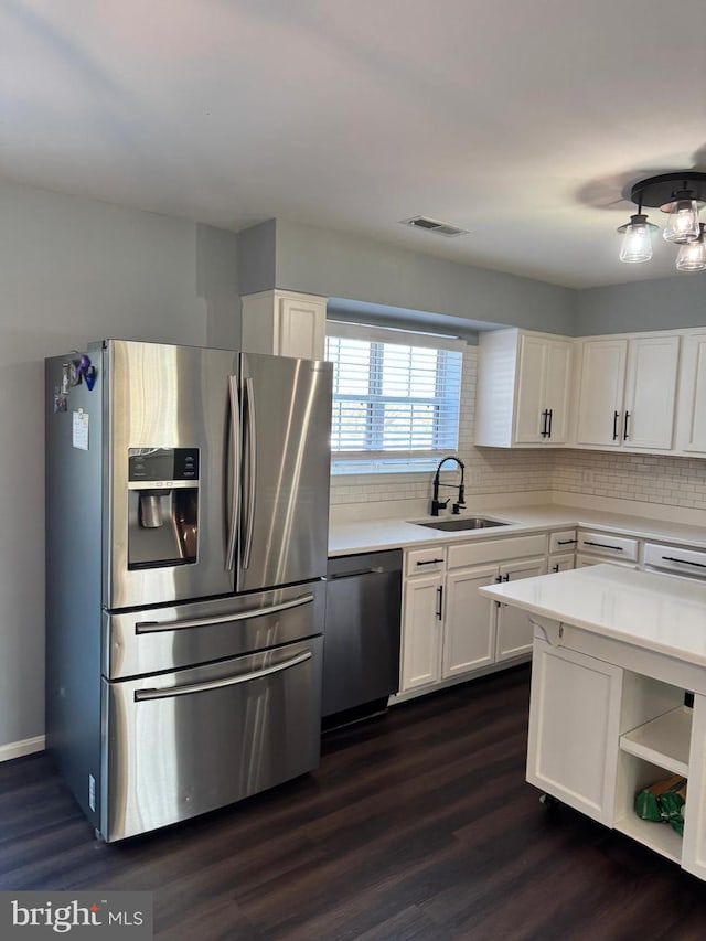 kitchen featuring sink, appliances with stainless steel finishes, tasteful backsplash, white cabinets, and dark hardwood / wood-style flooring