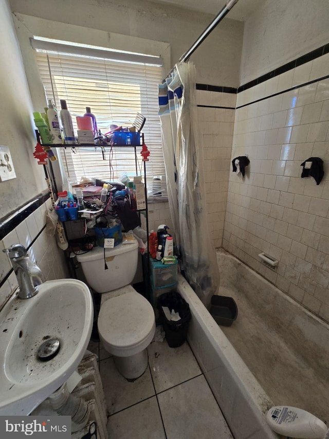 full bathroom with shower / tub combo with curtain, sink, tile walls, tile patterned flooring, and toilet