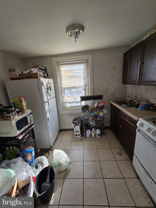 kitchen with dark brown cabinets, sink, light tile patterned floors, and white appliances