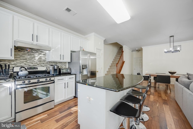 kitchen featuring white cabinetry, a center island, hanging light fixtures, a kitchen breakfast bar, and stainless steel appliances