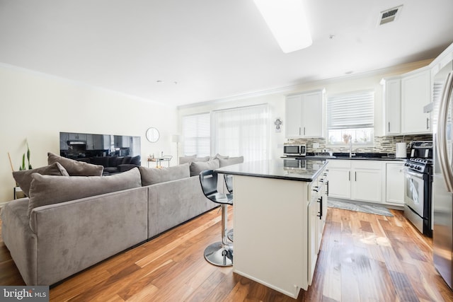 kitchen with stainless steel appliances, a center island, white cabinets, and light hardwood / wood-style floors