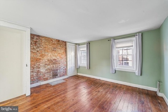 spare room with wood-type flooring and brick wall