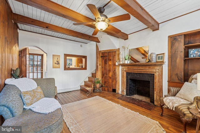 living room featuring ceiling fan, wood-type flooring, wooden ceiling, and beamed ceiling