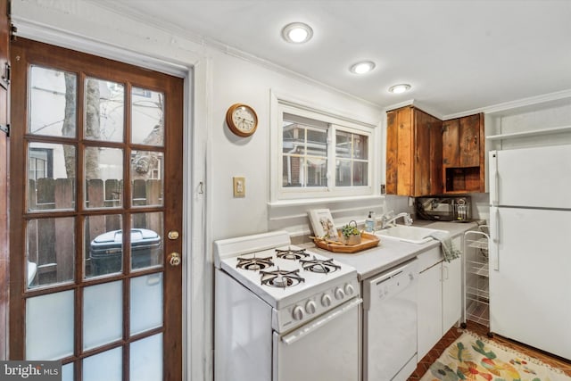 kitchen with crown molding, white appliances, and sink