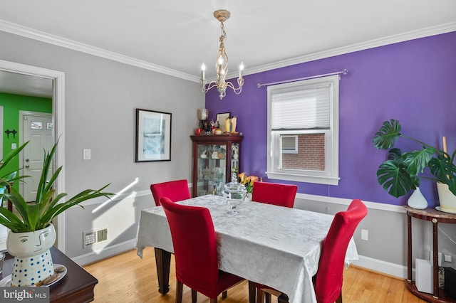 dining area featuring crown molding, a notable chandelier, and light hardwood / wood-style floors