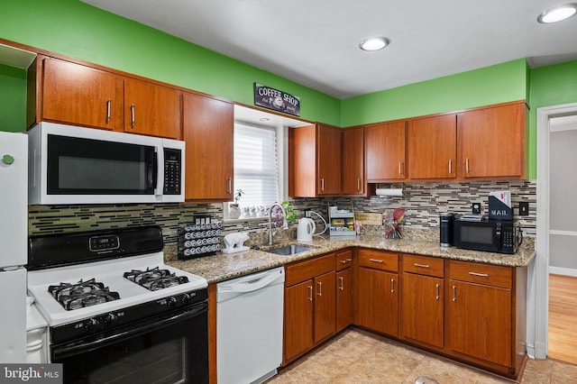 kitchen featuring light stone counters, sink, white appliances, and decorative backsplash