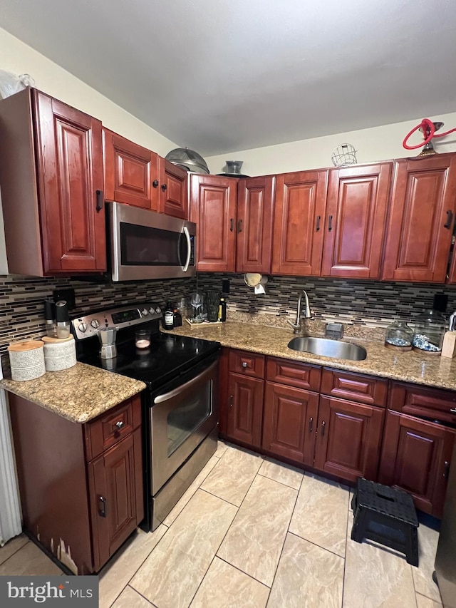 kitchen featuring sink, backsplash, light stone countertops, and appliances with stainless steel finishes