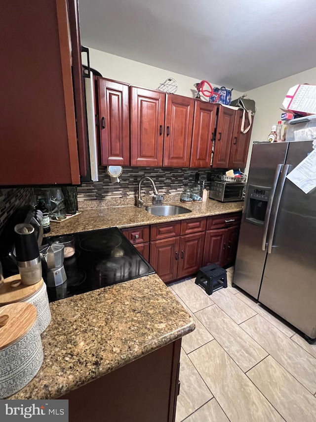 kitchen featuring stone countertops, sink, backsplash, stainless steel fridge with ice dispenser, and light tile patterned floors