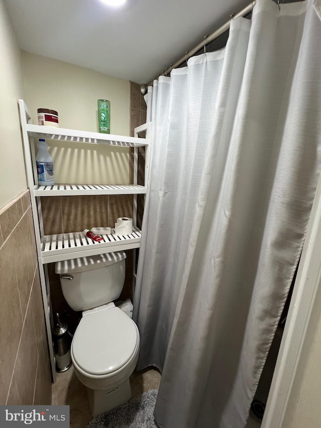 bathroom featuring toilet and tile walls