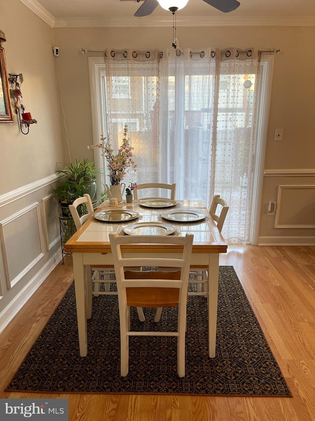 dining space with ceiling fan, light hardwood / wood-style flooring, ornamental molding, and a healthy amount of sunlight