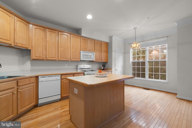 kitchen featuring white appliances, a kitchen island, an inviting chandelier, light countertops, and a sink