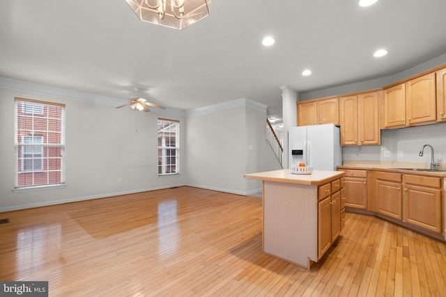 kitchen featuring a center island, white refrigerator with ice dispenser, light countertops, light wood-style floors, and a sink