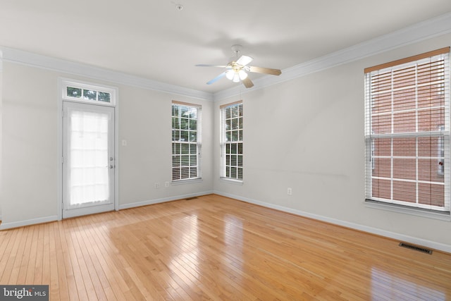 spare room featuring ornamental molding, visible vents, light wood-style flooring, and baseboards