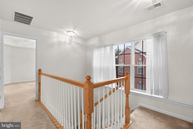 hall featuring carpet flooring, an upstairs landing, and visible vents