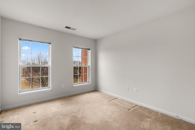 carpeted spare room with visible vents and baseboards