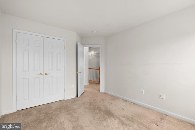 unfurnished bedroom featuring carpet, baseboards, and a closet