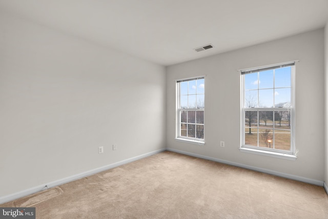 carpeted empty room featuring baseboards and visible vents