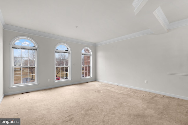 empty room with carpet floors, visible vents, crown molding, and baseboards