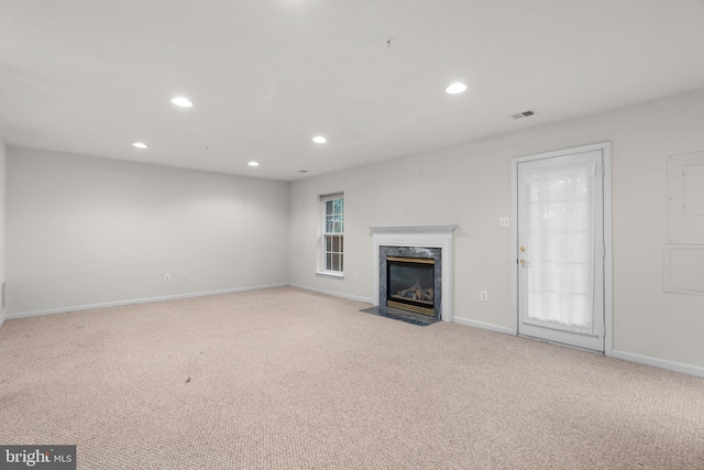 unfurnished living room with visible vents, baseboards, a high end fireplace, carpet floors, and recessed lighting