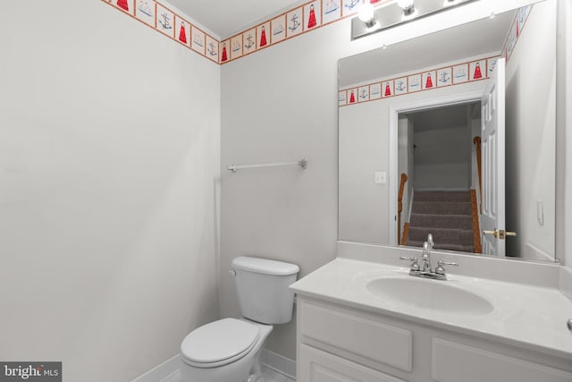 bathroom featuring toilet, vanity, and baseboards