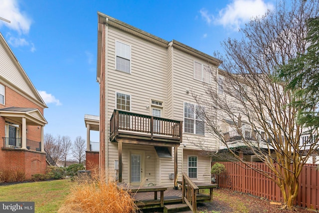 back of property featuring a deck, fence, and a balcony