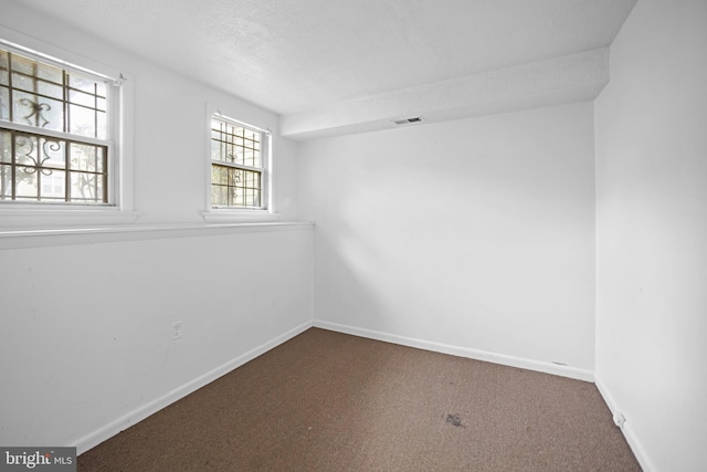 empty room with carpet floors and a textured ceiling