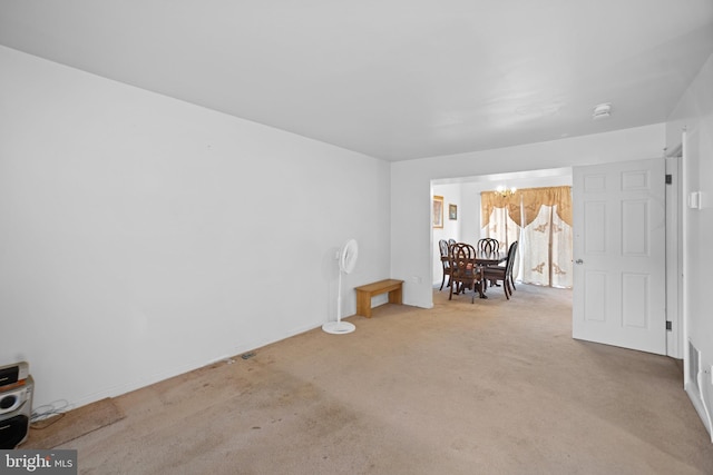 unfurnished room with light colored carpet and an inviting chandelier