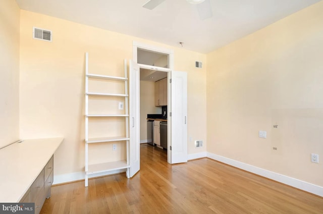 interior space featuring light wood finished floors, baseboards, visible vents, and ceiling fan