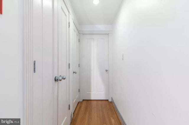 hallway featuring light wood-type flooring and baseboards