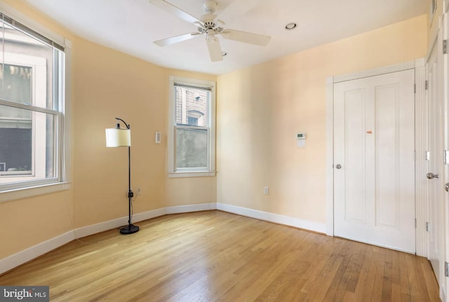 spare room with light wood-style floors, ceiling fan, and baseboards