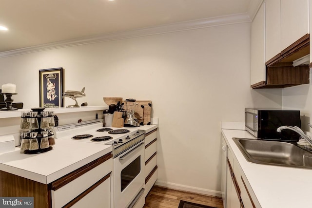 kitchen with electric stove, light countertops, a sink, and white cabinets